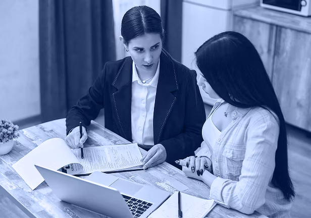 Two people comparing notes at a laptop